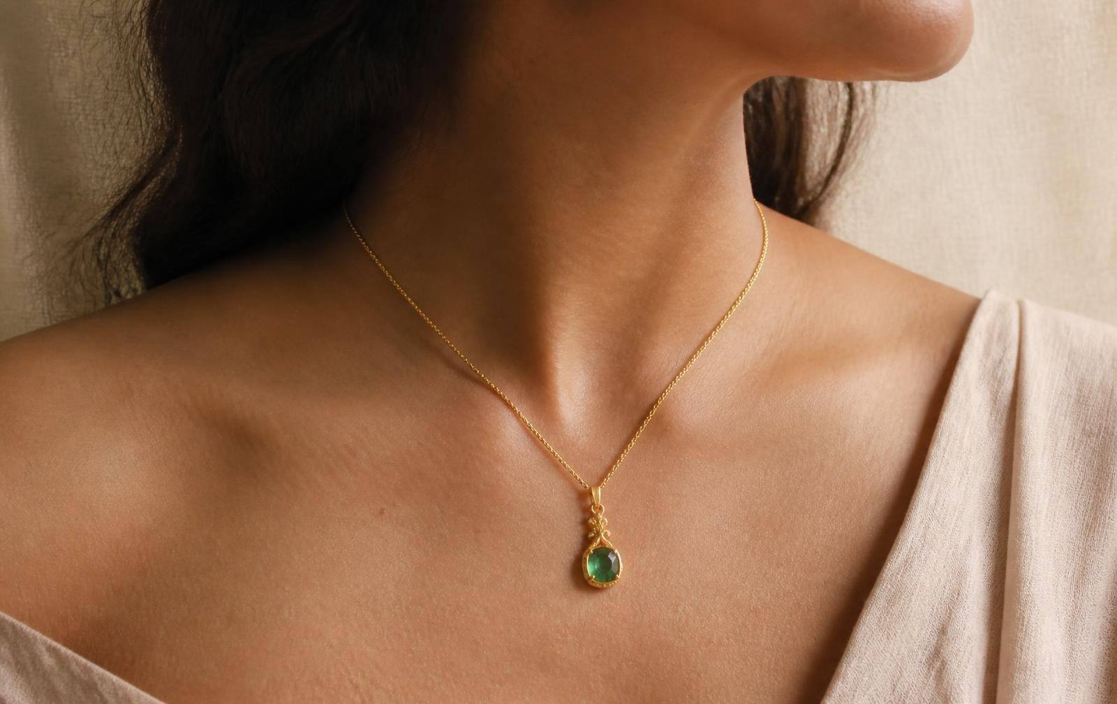 A 22K gold ring set with a natural emerald resting on deep green silk